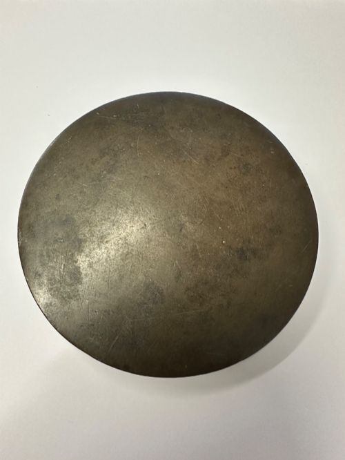 fig 2. A circular ancient bronze mirror back featuring a prominent central knob, raised concentric circular borders, and stylized dragon motifs in low relief.