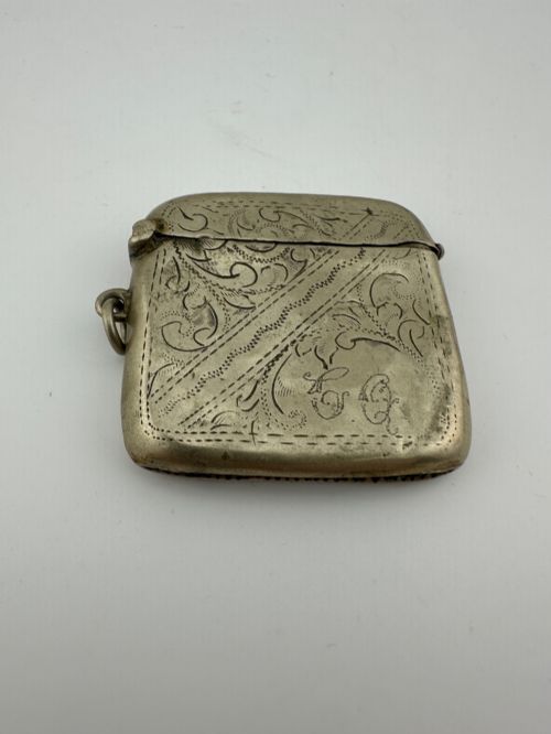 fig 2. An antique rectangular silver-plated vesta case featuring hand-engraved scrollwork, an open hinged lid, and a side suspension ring.