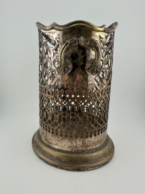 fig 1. An antique silver-plated cylindrical wine bottle holder featuring pierced scroll fretwork, two side handles, and a flared circular base.