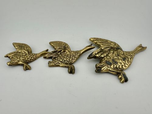 fig 1. A set of three graduated cast brass flying geese wall plaques arranged by size with textured feather detailing.