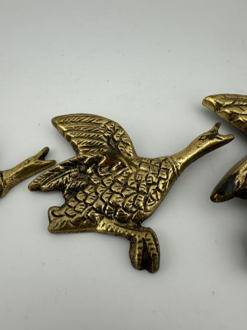 fig 3. A set of three graduated cast brass flying geese wall plaques arranged by size with textured feather detailing.