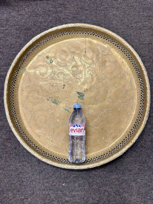 fig 2. A circular antique brass tray featuring an intricately engraved swirling floral pattern and a pierced gallery rim.