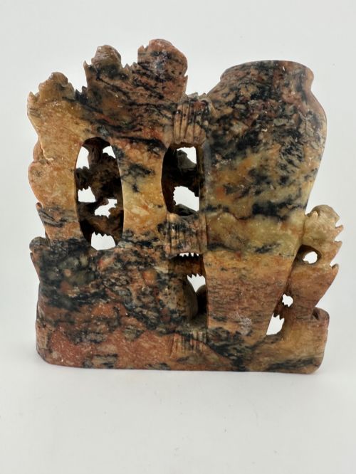 fig 4. A Qing dynasty Chinese soapstone carving depicting a small vase, a shallow brush washer basin, and carved birds among naturalistic floral motifs in mottled red, grey, and cream stone.