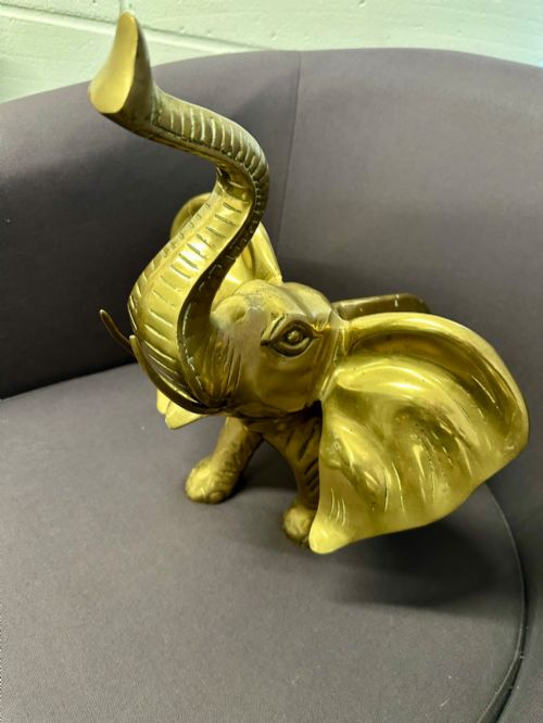 fig 2. A solid brass sculpture of an elephant standing with its trunk raised up.