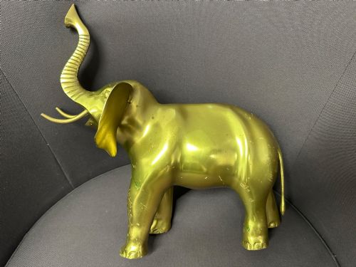 fig 1. A vintage cast brass elephant sculpture standing with its trunk raised high.