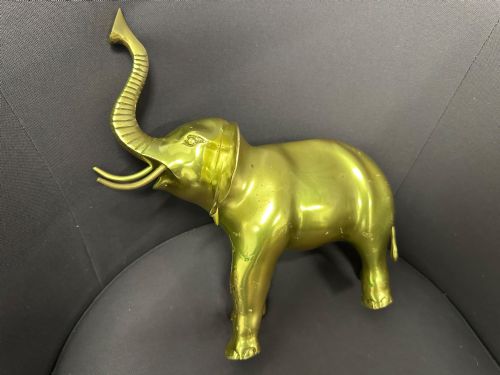 fig 2. A vintage cast brass elephant sculpture standing with its trunk raised high.