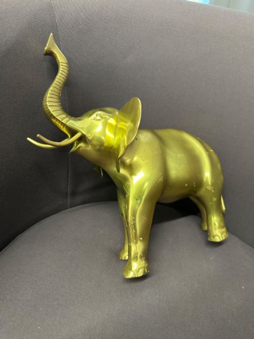 fig 3. A vintage cast brass elephant sculpture standing with its trunk raised high.