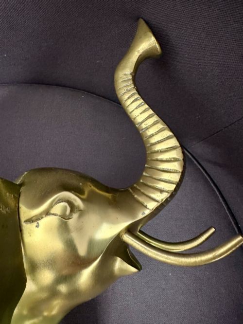 fig 8. A vintage cast brass elephant sculpture standing with its trunk raised high.
