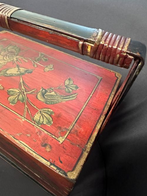 fig 1. A three-tiered Chinese red lacquer wedding basket featuring hand-painted gold floral motifs and a black wooden carrying handle.