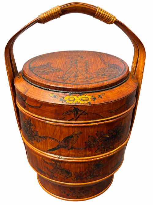 fig 1. A late Qing Dynasty tiered Chinese food basket crafted from warm amber bamboo and wood, hand-painted with black line illustrations of a child on the lid and floral motifs around the body.