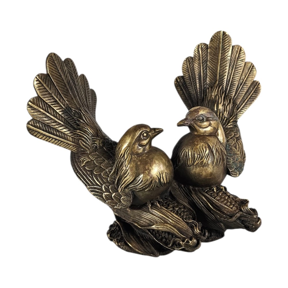 A pair of cast bronze doves with detailed feather chasing and fanned tail feathers perched together on a maize cob base.