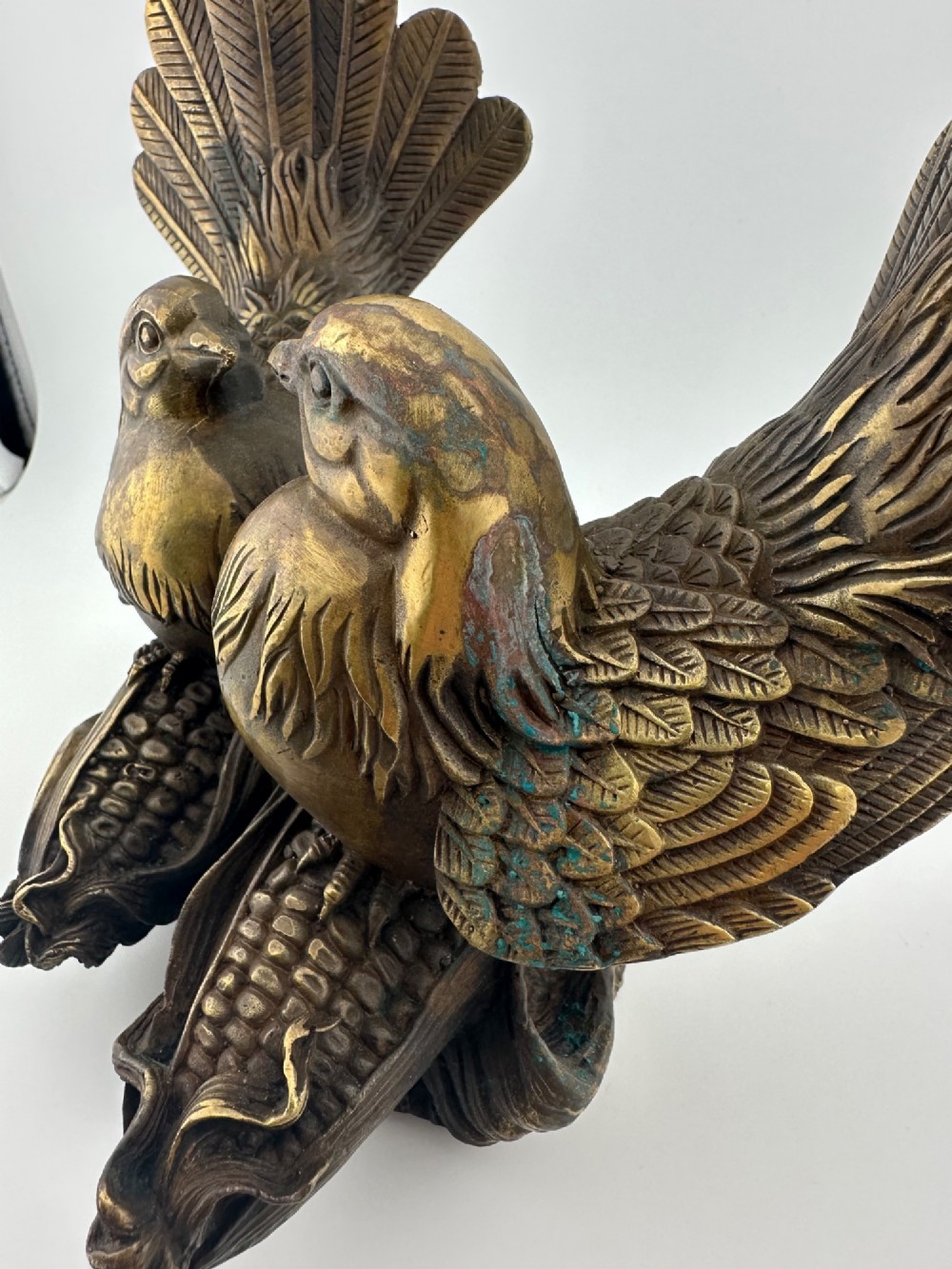 A pair of cast bronze doves with detailed feather chasing and fanned tail feathers perched together on a maize cob base. View V