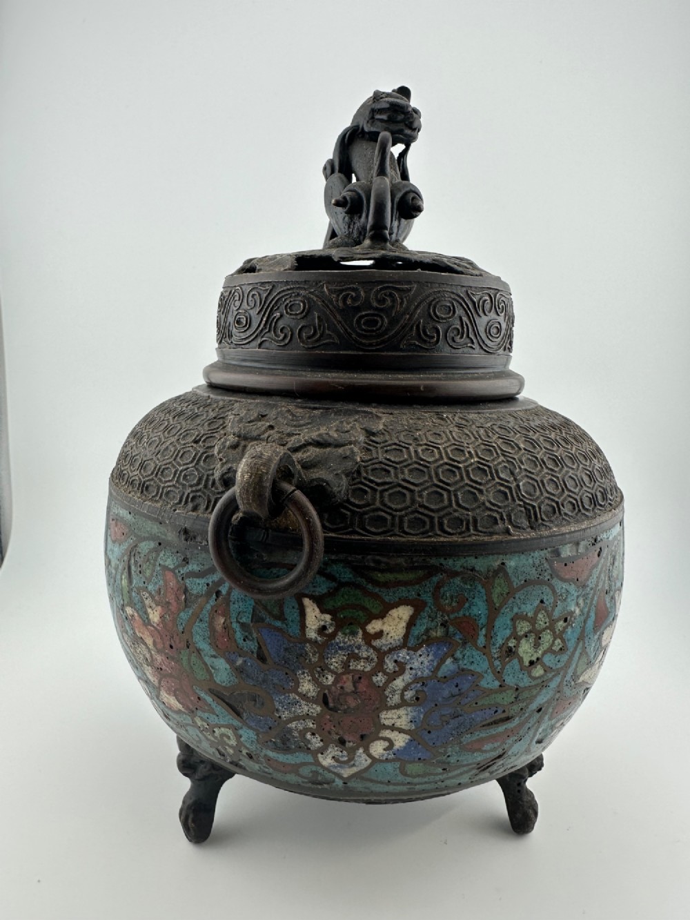 A 19th-century Chinese bronze tripod censer featuring polychrome cloisonne enamel floral motifs, side loop handles, and a lid topped with a Qilin finial. View III