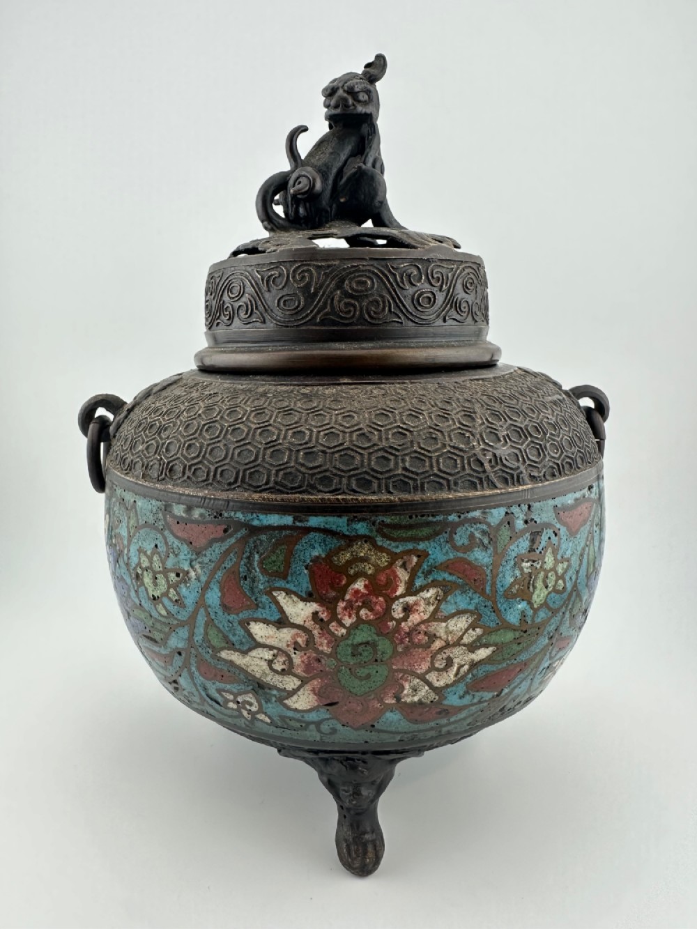 A 19th-century Chinese bronze tripod censer featuring polychrome cloisonne enamel floral motifs, side loop handles, and a lid topped with a Qilin finial. View IV