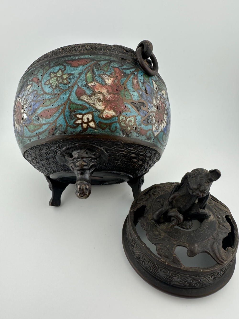 A 19th-century Chinese bronze tripod censer featuring polychrome cloisonne enamel floral motifs, side loop handles, and a lid topped with a Qilin finial. View VIII