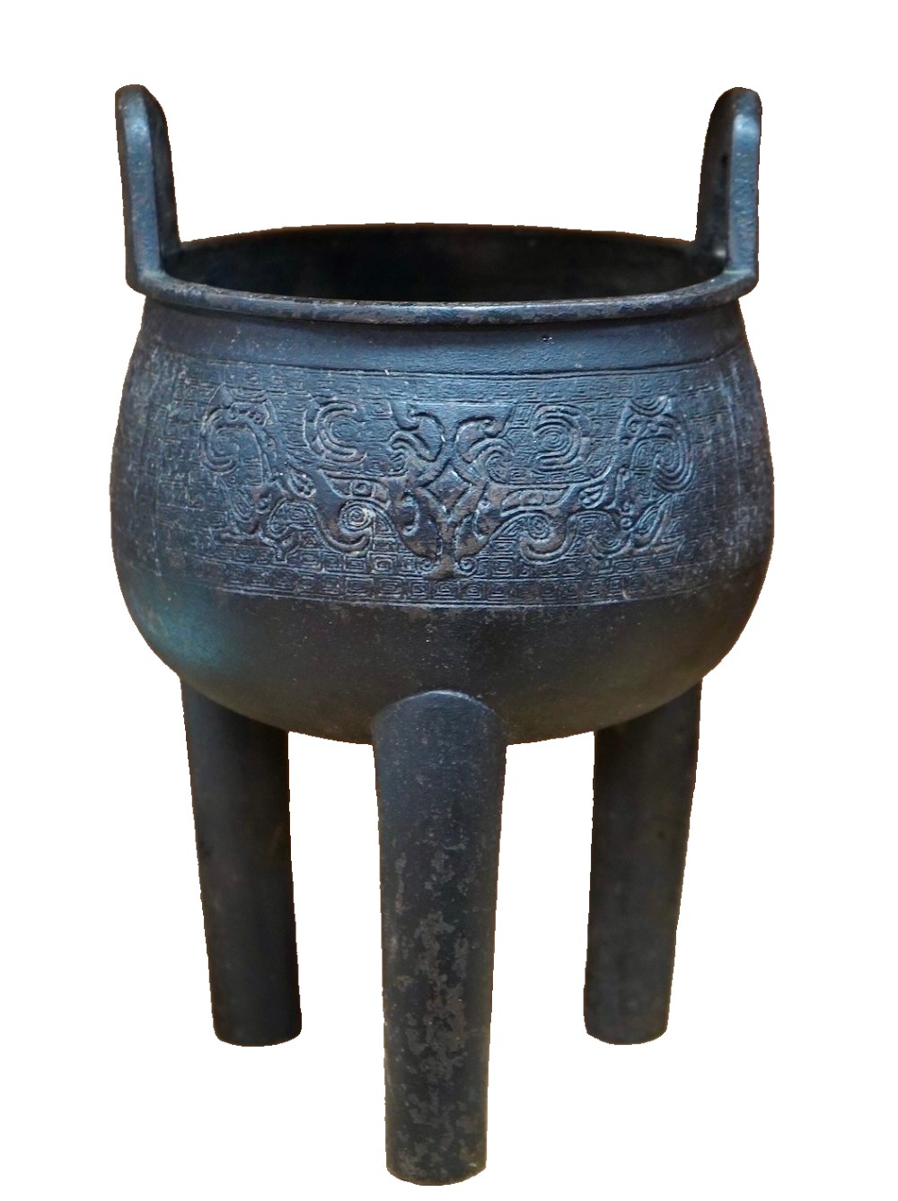 A dark patinated bronze tripod ding censer featuring three cylindrical legs, twin upright handles, and carved taotie mask relief decoration around the upper body. View II