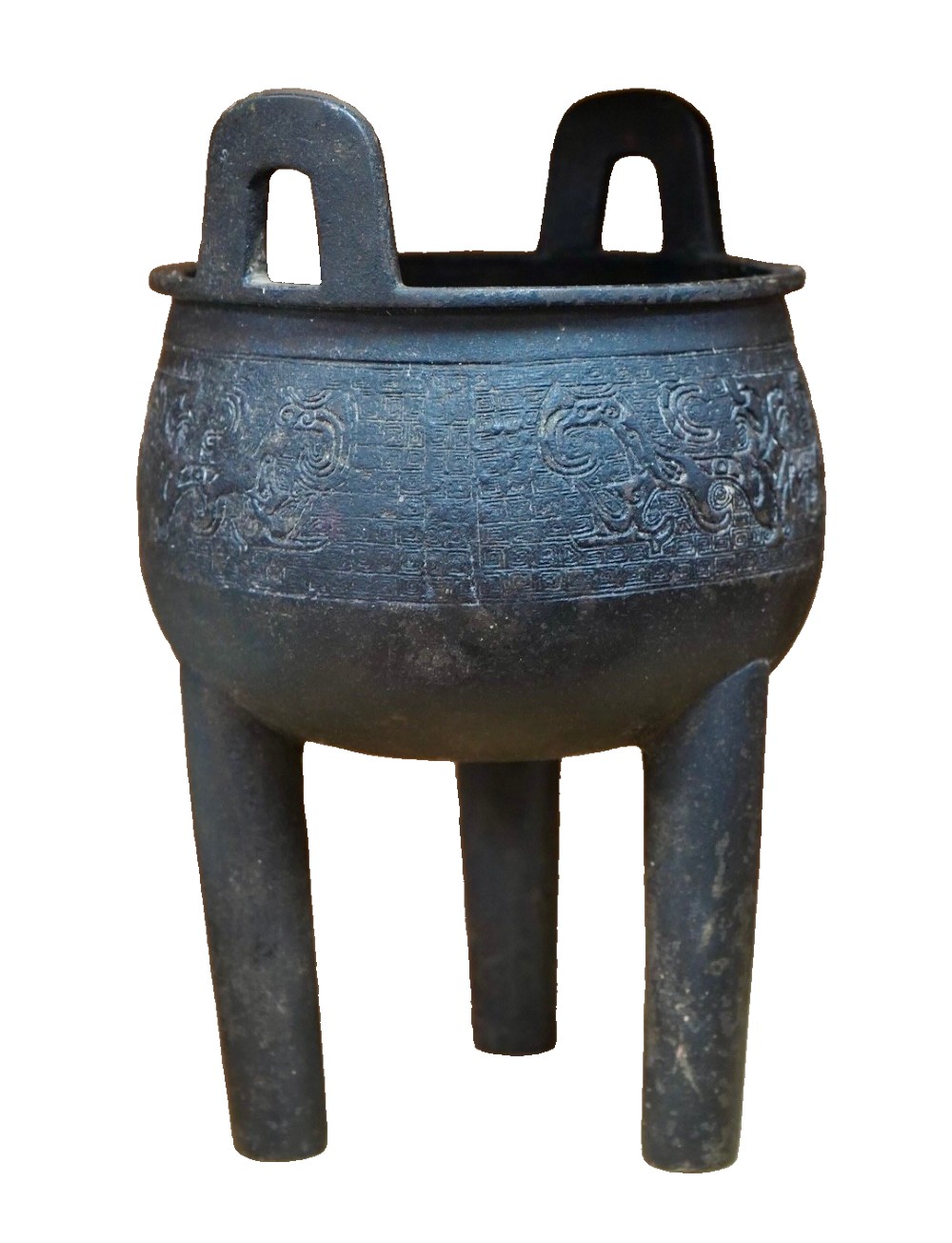 A dark patinated bronze tripod ding censer featuring three cylindrical legs, twin upright handles, and carved taotie mask relief decoration around the upper body. View III