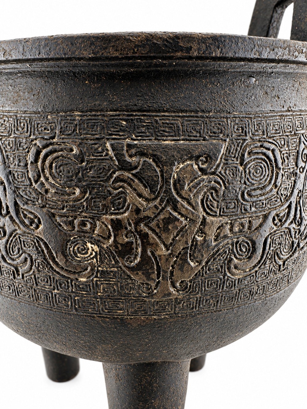 A dark patinated bronze tripod ding censer featuring three cylindrical legs, twin upright handles, and carved taotie mask relief decoration around the upper body. View IV