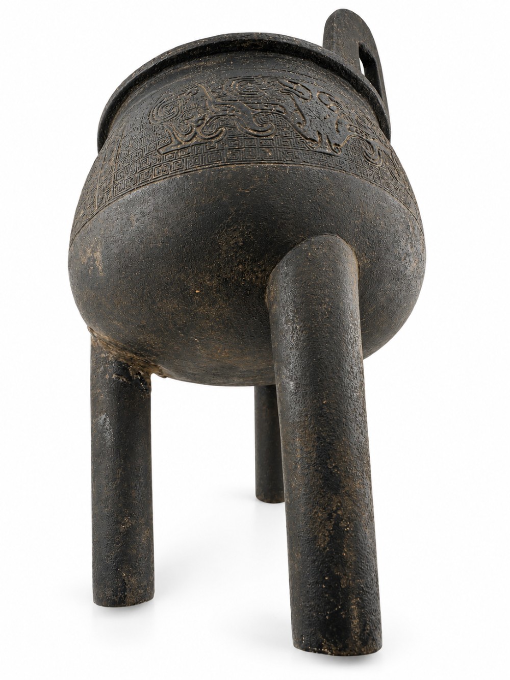 A dark patinated bronze tripod ding censer featuring three cylindrical legs, twin upright handles, and carved taotie mask relief decoration around the upper body. View VI