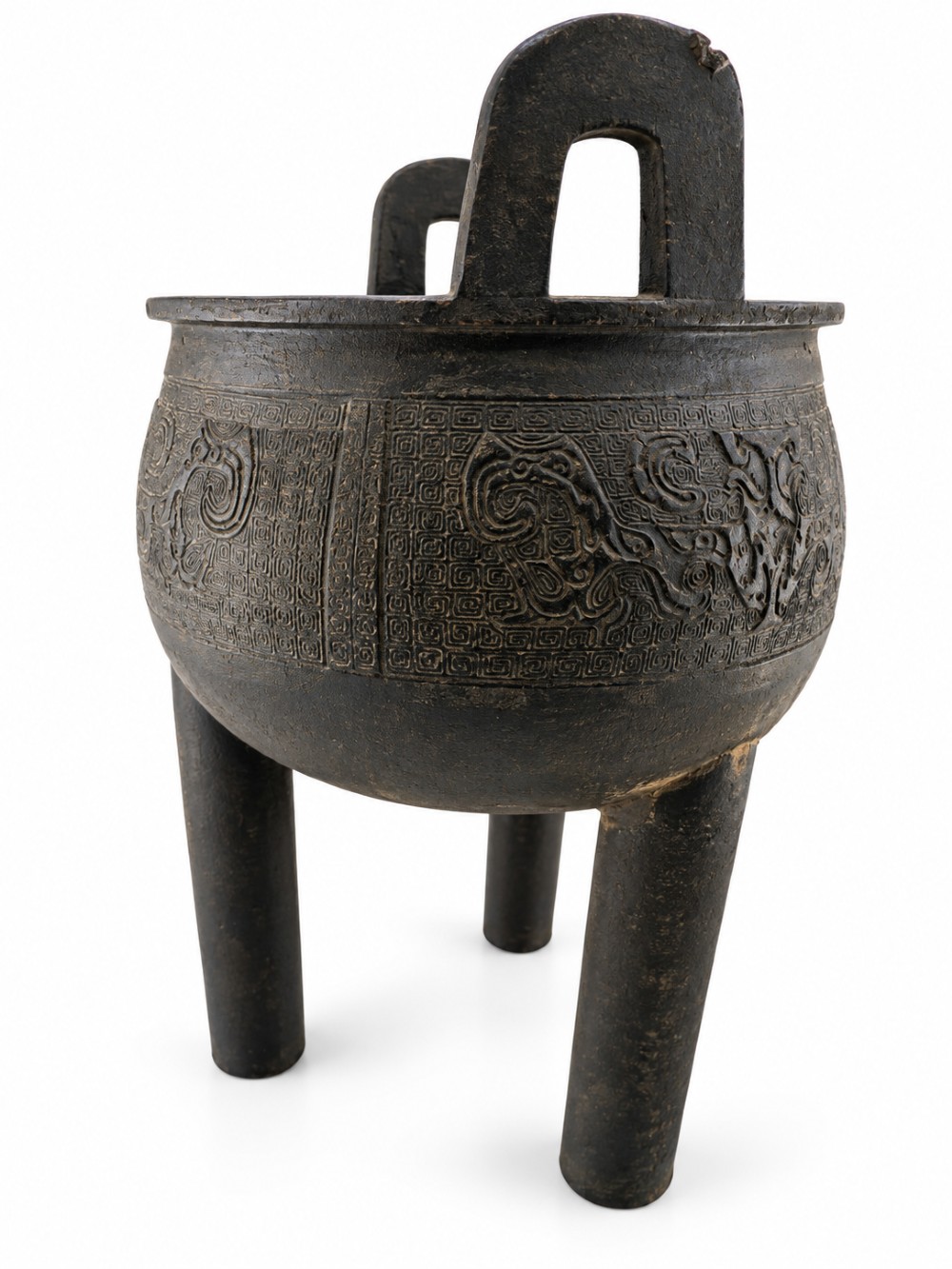 A dark patinated bronze tripod ding censer featuring three cylindrical legs, twin upright handles, and carved taotie mask relief decoration around the upper body. View VII