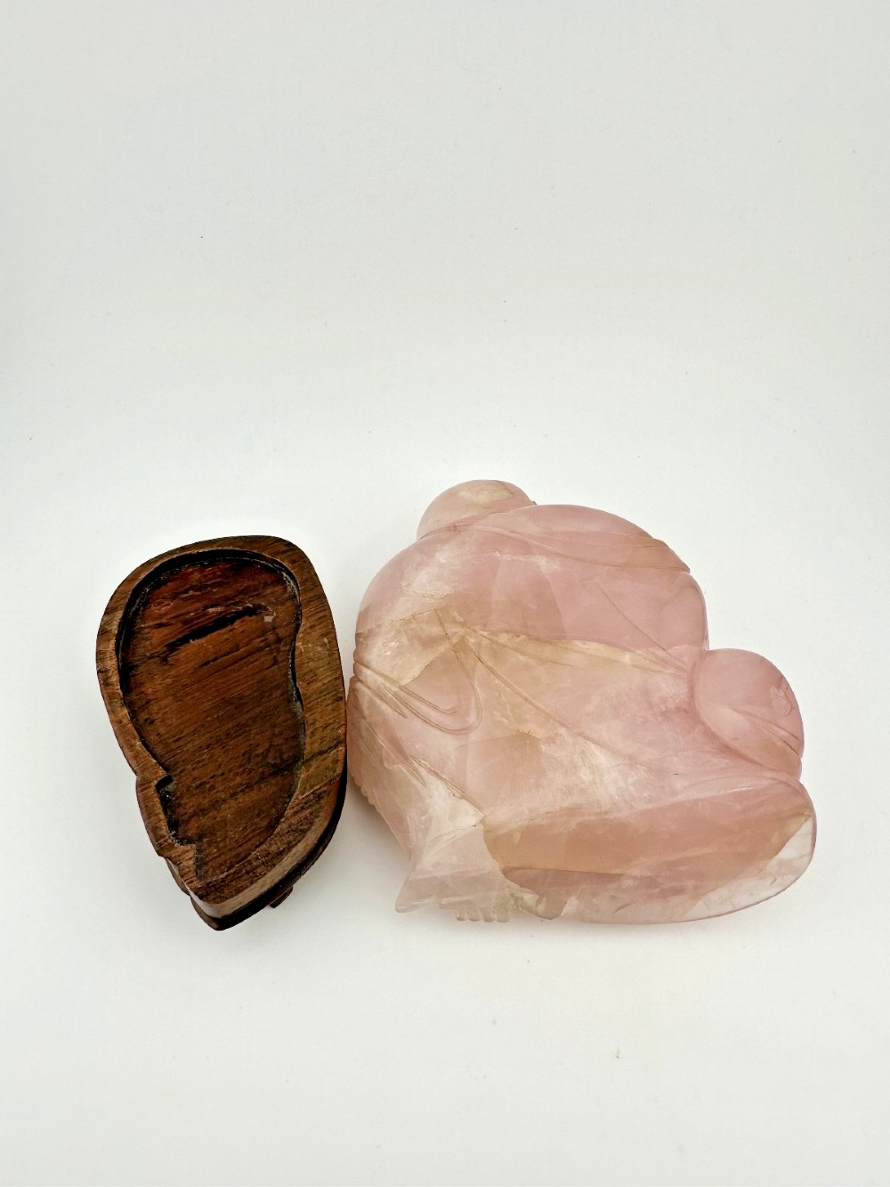 A hand-carved pink rose quartz figure of a seated Laughing Buddha resting upon a custom dark wood stand. View VI