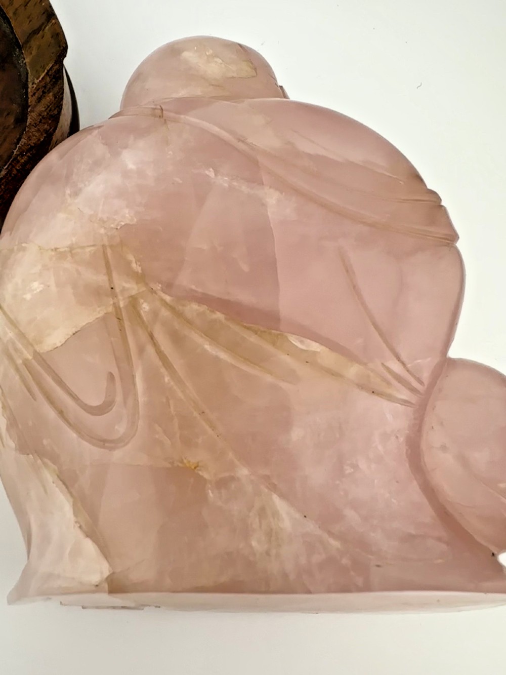 A hand-carved pink rose quartz figure of a seated Laughing Buddha resting upon a custom dark wood stand. View VIII