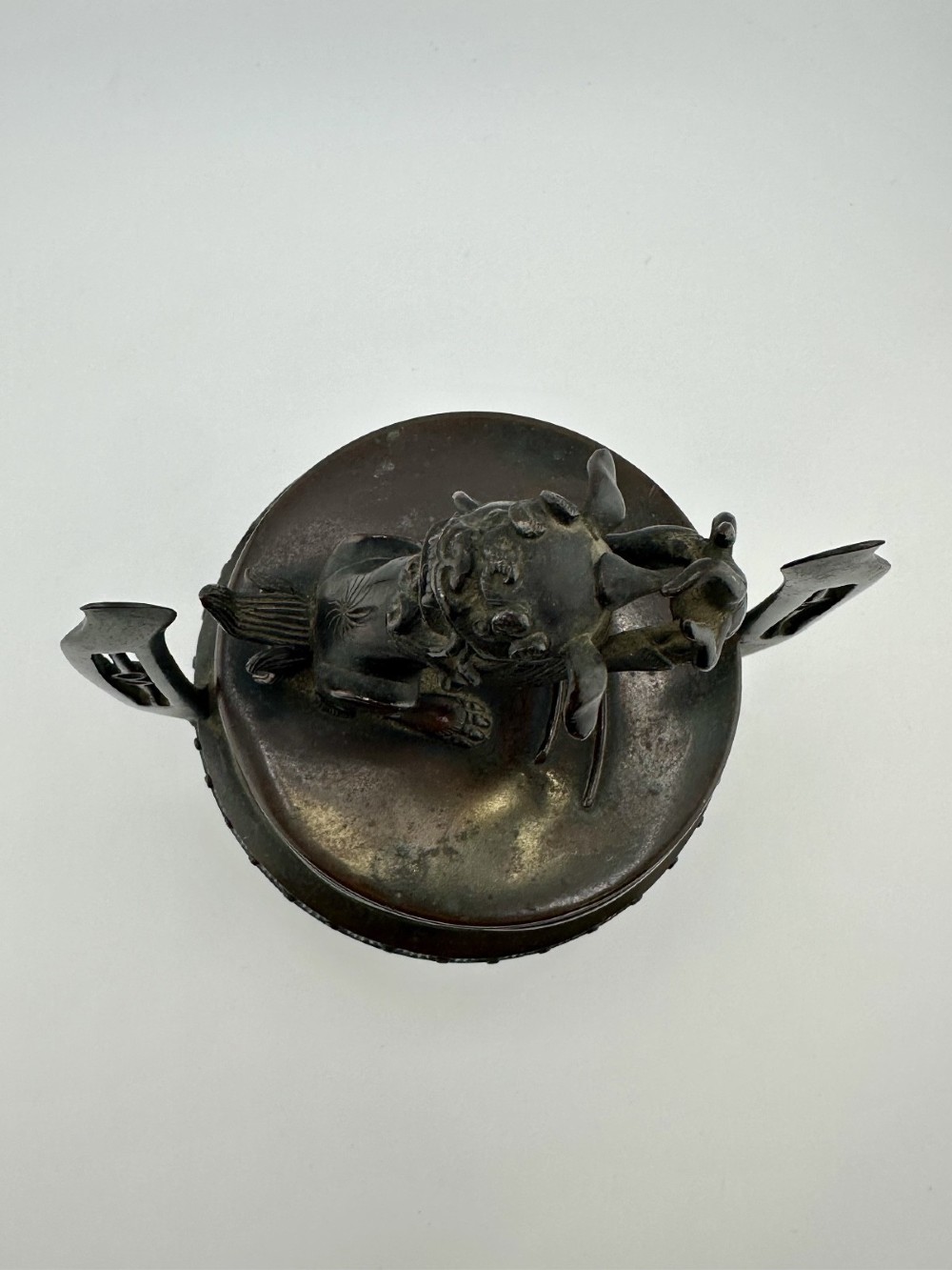 A dark patinated bronze tripod censer featuring raised loop handles, a decorative meander border, and a fitted lid with a standing Qilin finial. View IV
