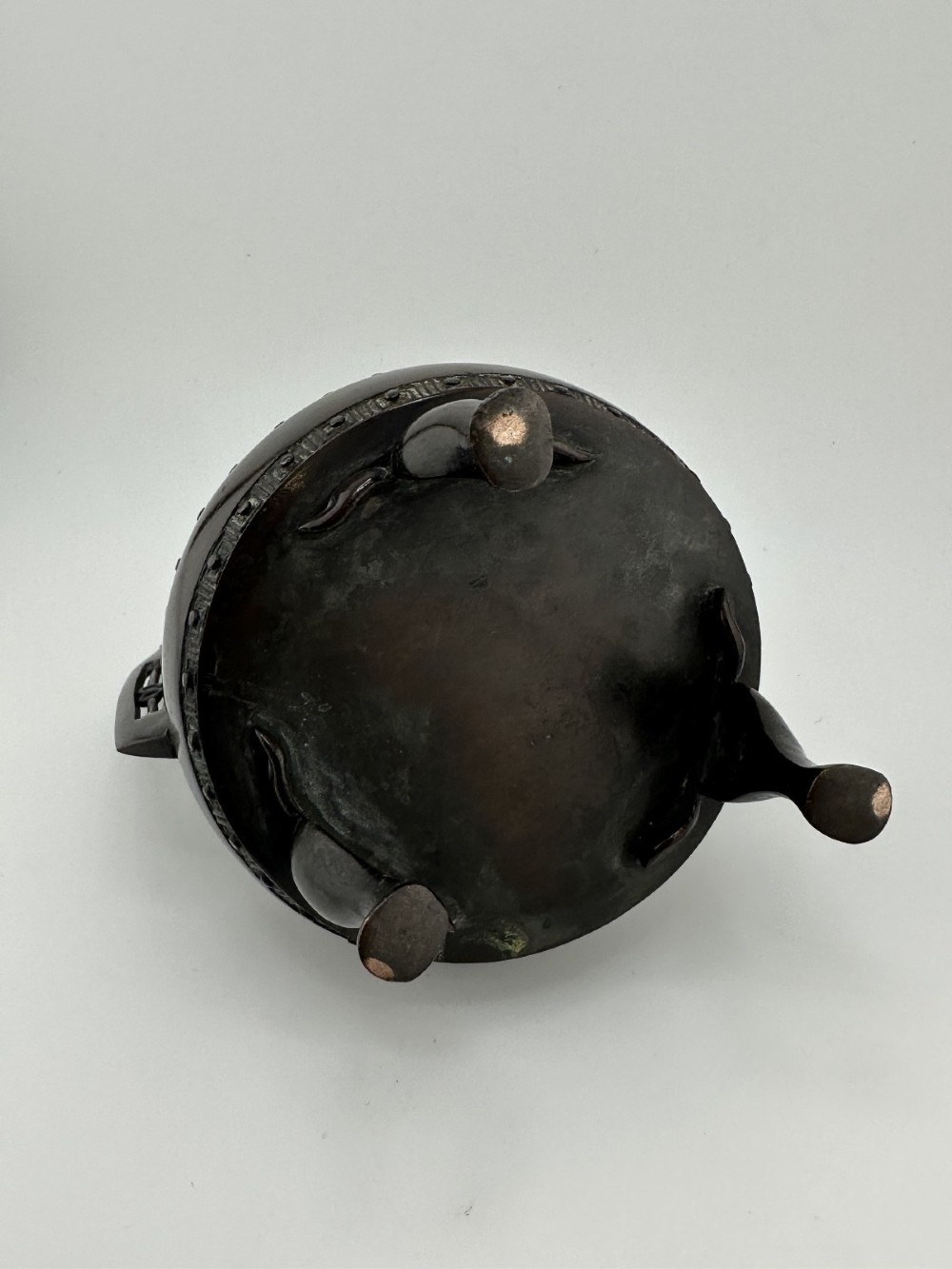 A dark patinated bronze tripod censer featuring raised loop handles, a decorative meander border, and a fitted lid with a standing Qilin finial. View VIII