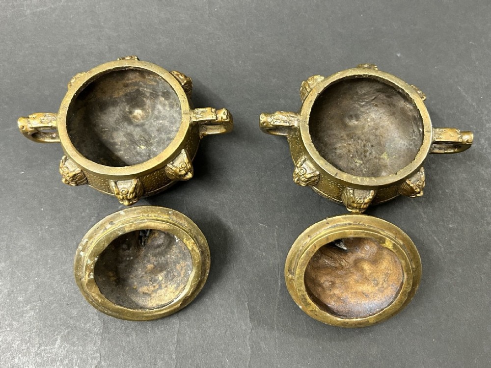 A pair of patinated bronze tripod censers featuring sculpted dragon finials on the lids, side handles, and relief mask carvings around the circular bodies. View III