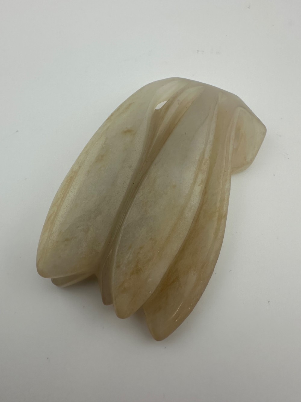 A carved pale celadon jade sculpture depicting a cicada with folded wings and smooth polished surfaces.