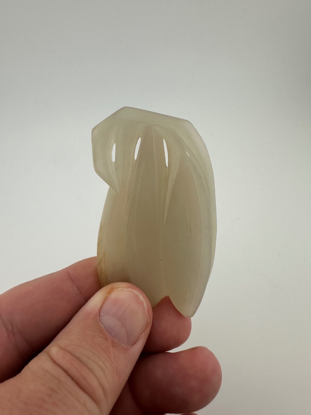 A carved pale celadon jade sculpture depicting a cicada with folded wings and smooth polished surfaces. View IV