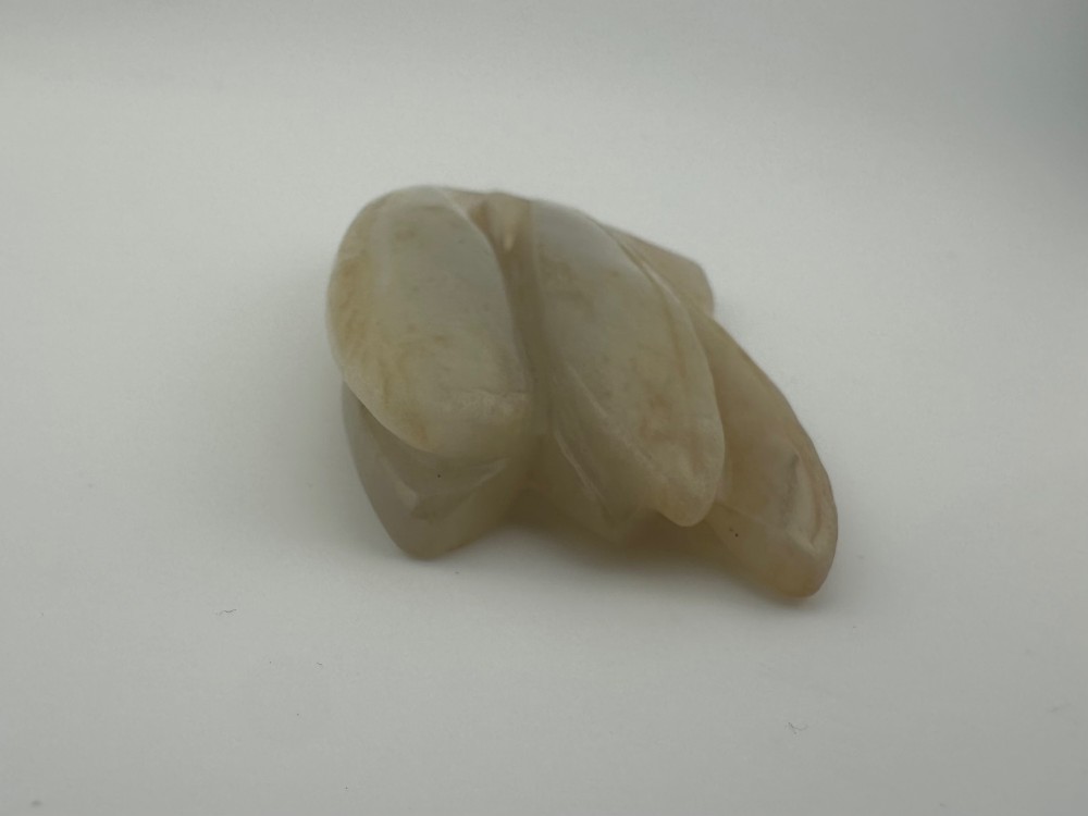 A carved pale celadon jade sculpture depicting a cicada with folded wings and smooth polished surfaces. View V