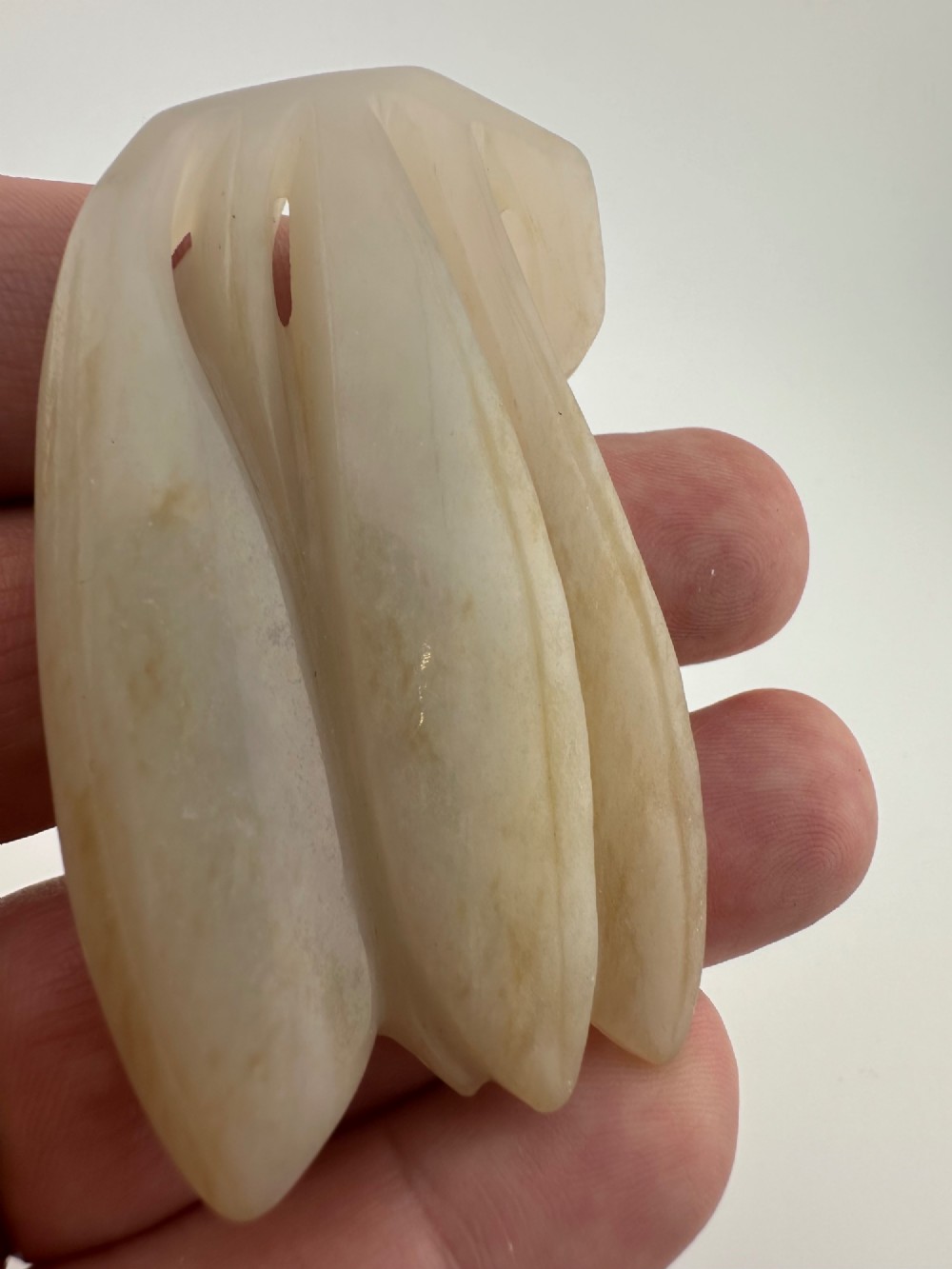 A carved pale celadon jade sculpture depicting a cicada with folded wings and smooth polished surfaces. View VI