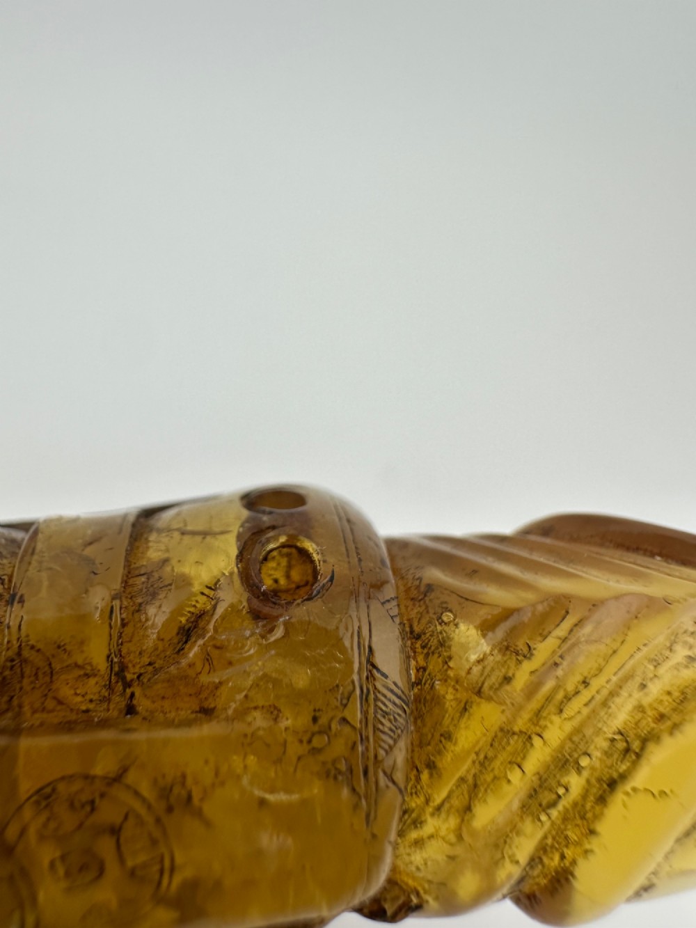 A hand-carved honey amber pendant depicting the Chinese deity Shoulao with incised robe detailing and a high domed head. View V