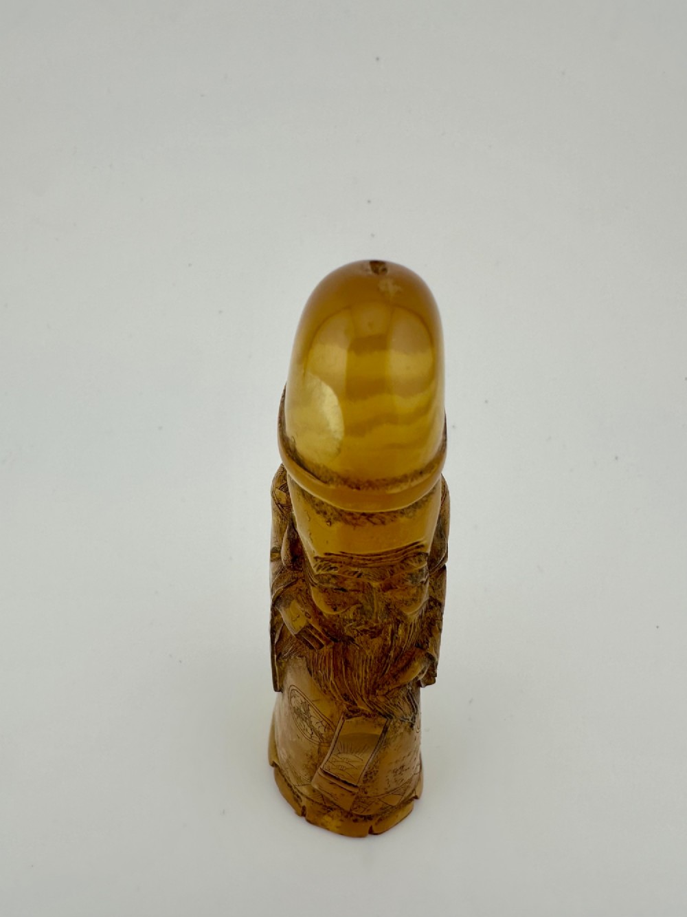 A hand-carved honey amber pendant depicting the Chinese deity Shoulao with incised robe detailing and a high domed head. View XI