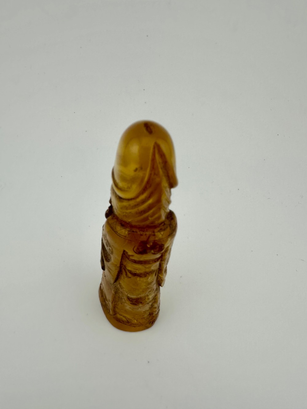 A hand-carved honey amber pendant depicting the Chinese deity Shoulao with incised robe detailing and a high domed head. View XIV