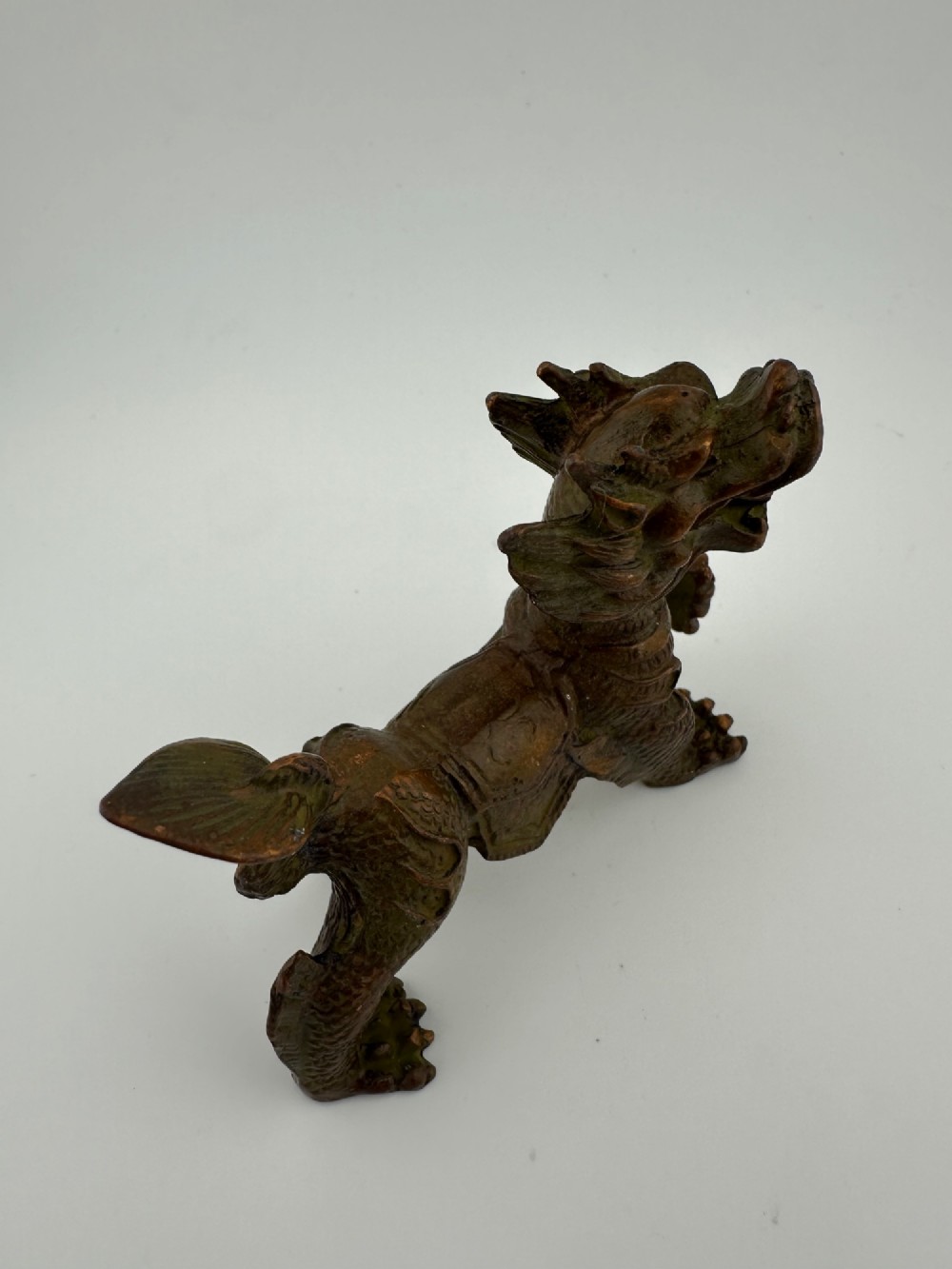 A small patinated dark brown bronze figure of a Chinese mythical beast, standing on four legs with an open mouth and raised tail. View III