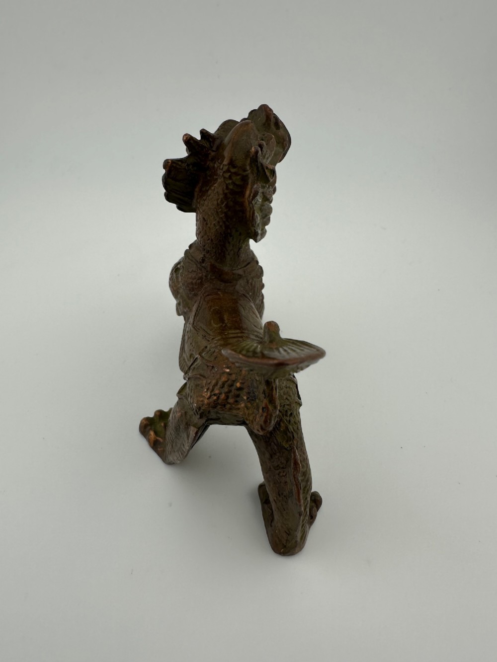 A small patinated dark brown bronze figure of a Chinese mythical beast, standing on four legs with an open mouth and raised tail. View IV