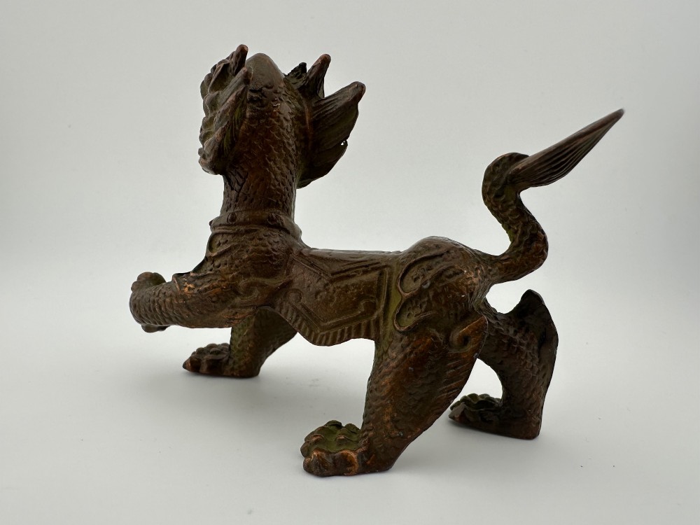 A small patinated dark brown bronze figure of a Chinese mythical beast, standing on four legs with an open mouth and raised tail. View V
