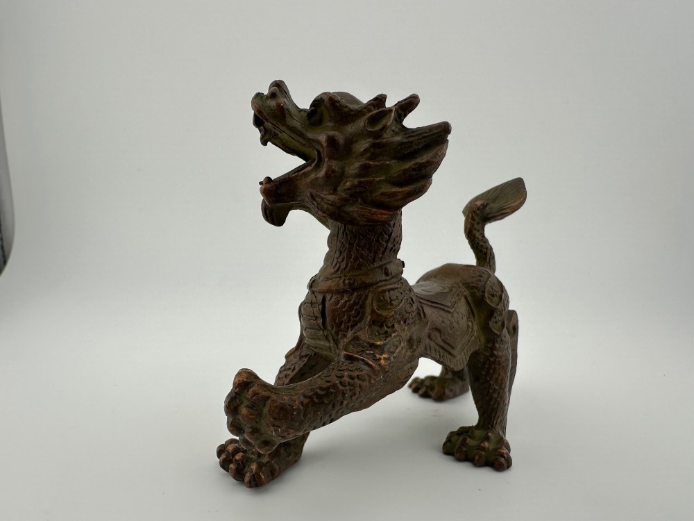 A small patinated dark brown bronze figure of a Chinese mythical beast, standing on four legs with an open mouth and raised tail. View VI