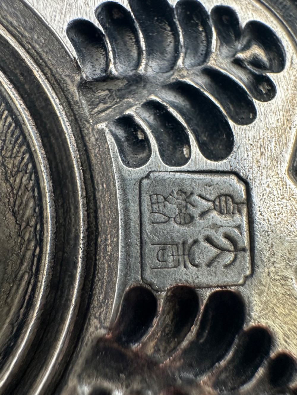 A lobed Chinese white metal dish with raised relief repousse lotus foliage and a central floral motif. View III