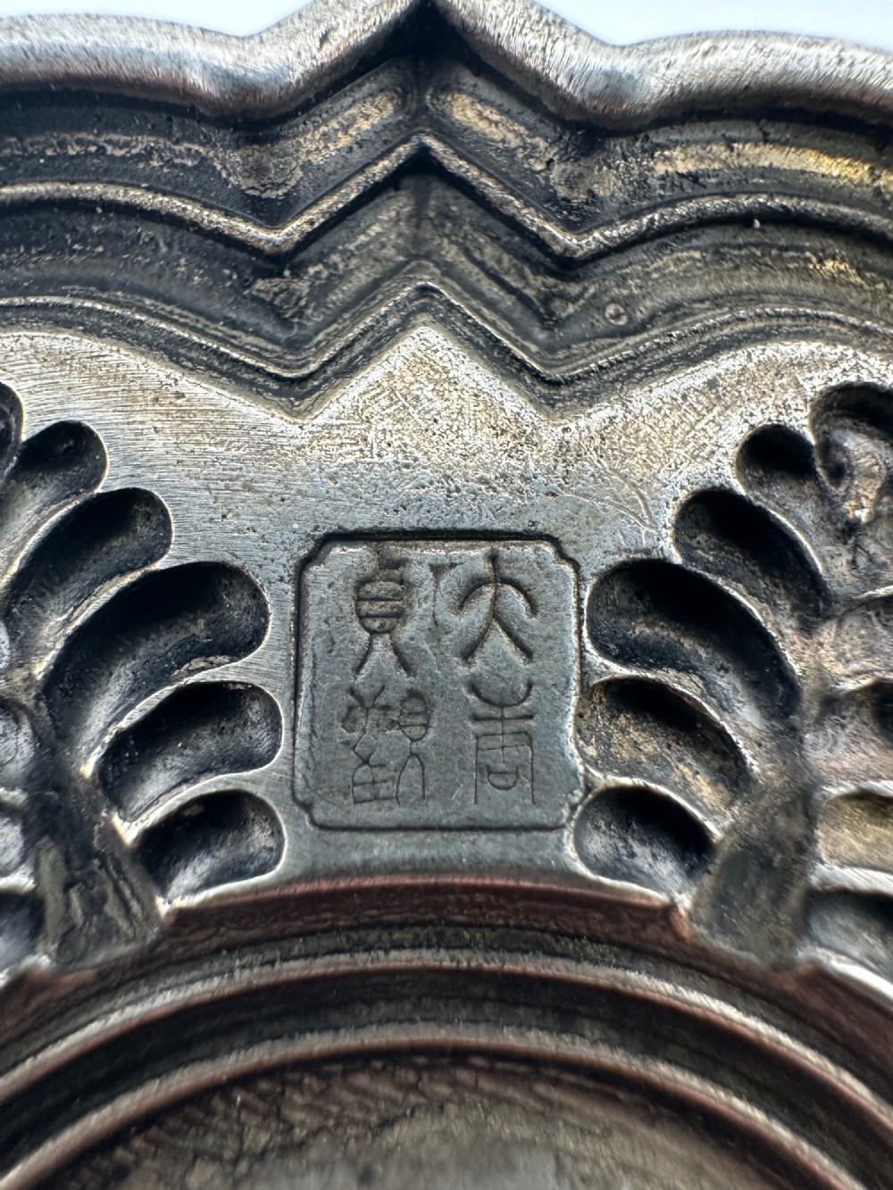 A lobed Chinese white metal dish with raised relief repousse lotus foliage and a central floral motif. View IV