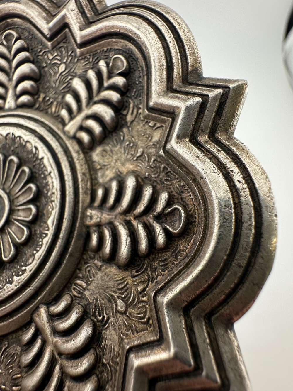 A lobed Chinese white metal dish with raised relief repousse lotus foliage and a central floral motif. View IX