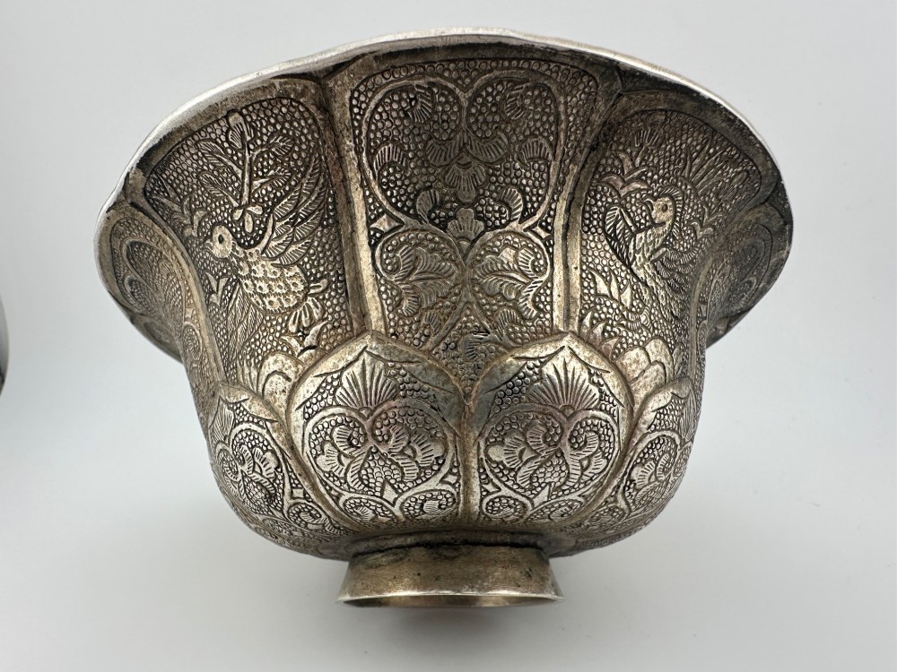 A lobed silver white metal bowl decorated with hand-chased panels of birds and flowers on a textured ground. View II