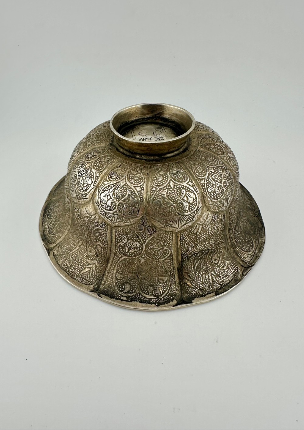 A lobed silver white metal bowl decorated with hand-chased panels of birds and flowers on a textured ground. View III