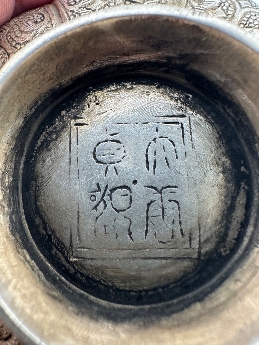 A lobed silver white metal bowl decorated with hand-chased panels of birds and flowers on a textured ground. View VI