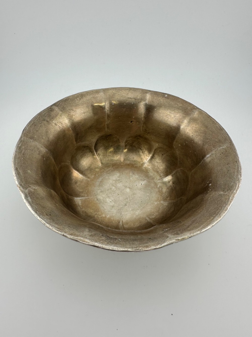 A lobed silver white metal bowl decorated with hand-chased panels of birds and flowers on a textured ground. View VII