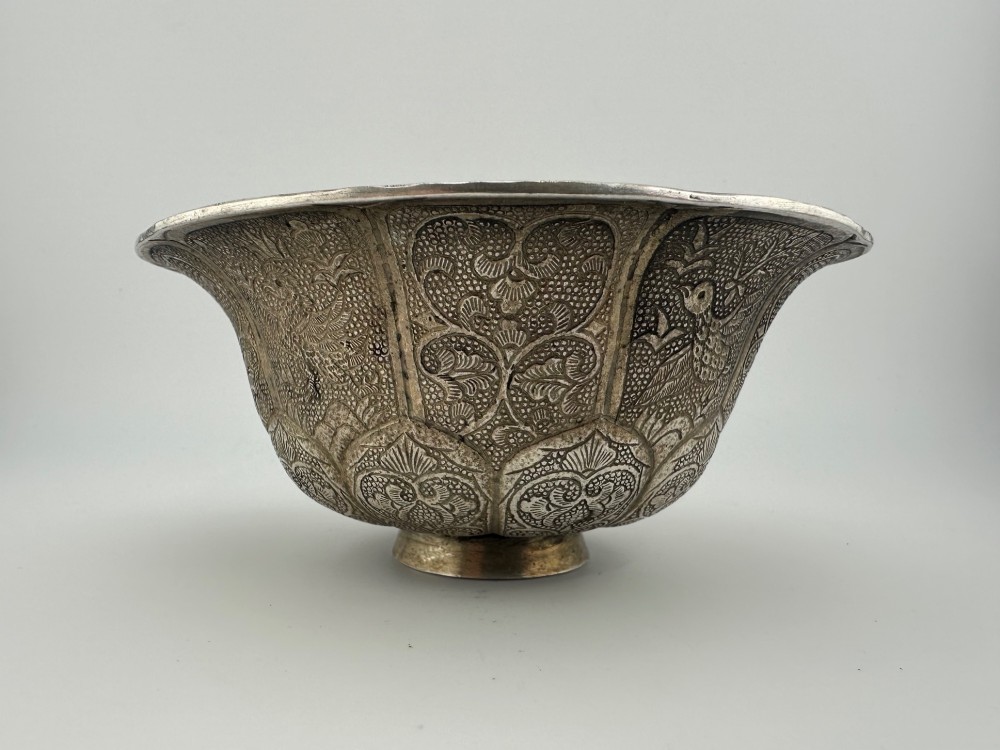 A lobed silver white metal bowl decorated with hand-chased panels of birds and flowers on a textured ground. View IX