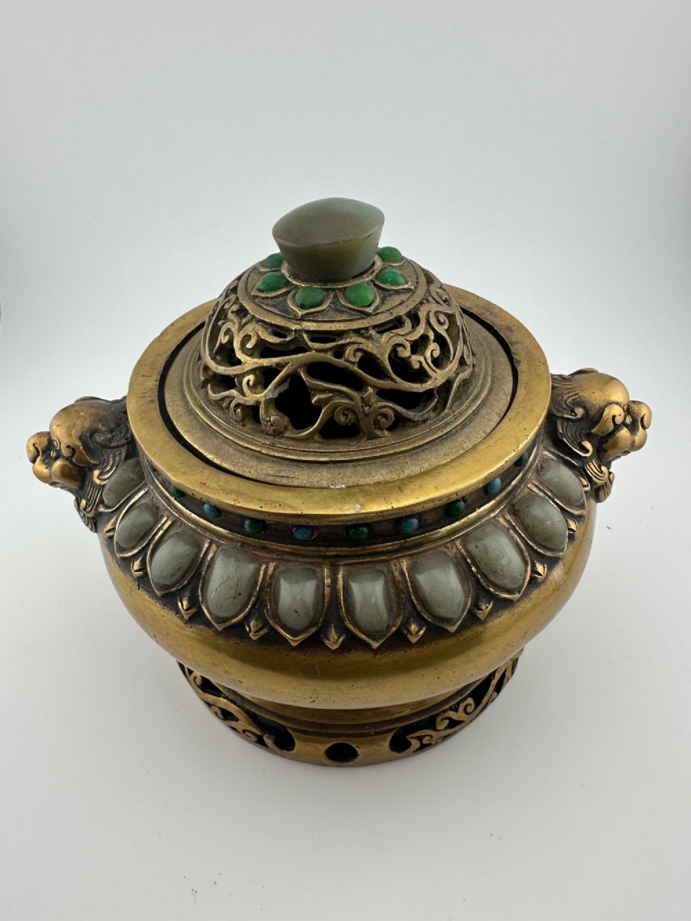 An antique gilded bronze Chinese censer featuring hardstone and jade cabochon inlays, beast-head handles, a pierced cover, and a matching carved stand. View II