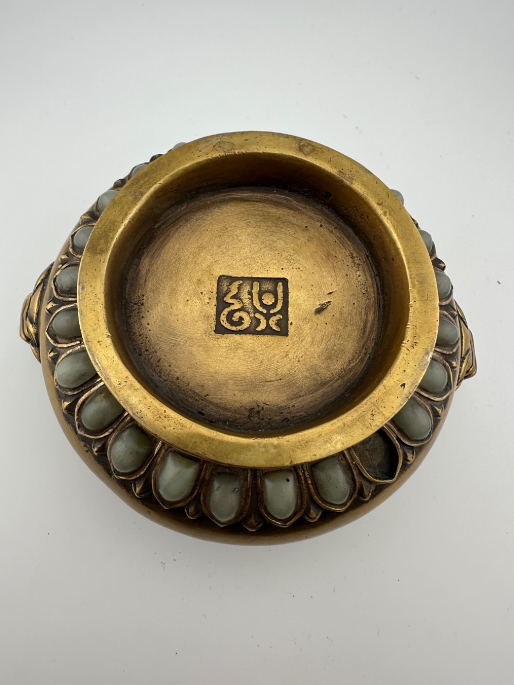 An antique gilded bronze Chinese censer featuring hardstone and jade cabochon inlays, beast-head handles, a pierced cover, and a matching carved stand. View V